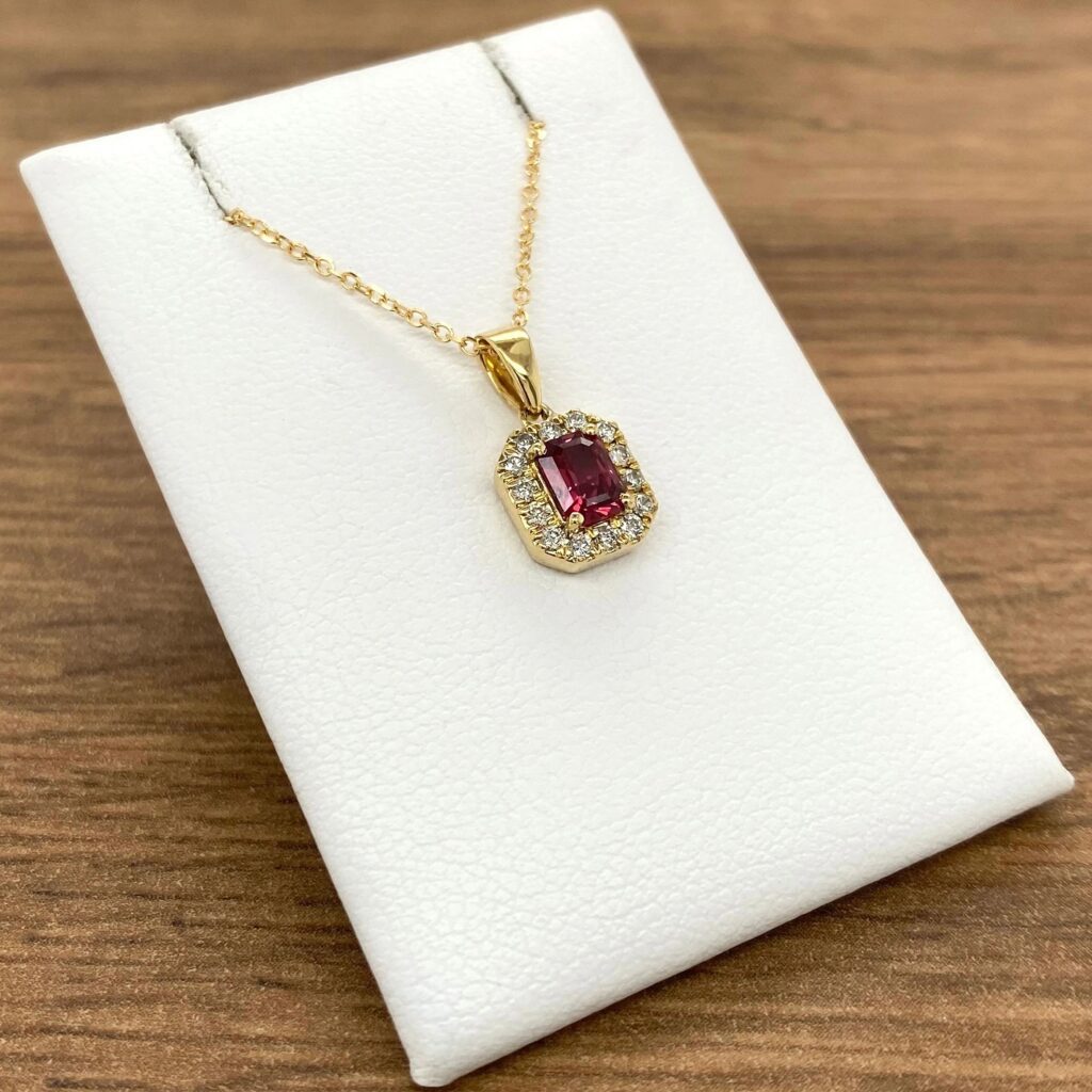 A pendant with a ruby stone and diamonds.