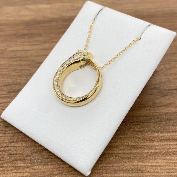 Gold necklace with emerald and diamond circle pendant.