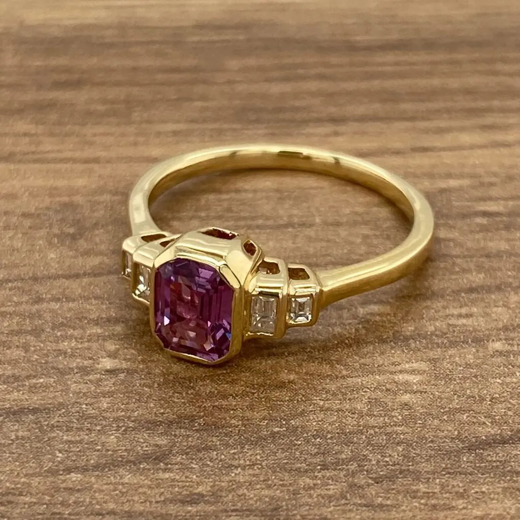 Gold ring with purple gemstone and diamonds.