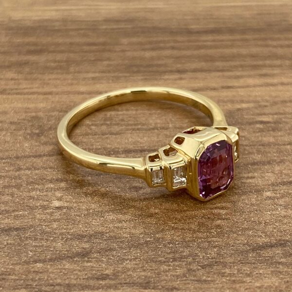 Gold ring with purple gemstone and diamonds.