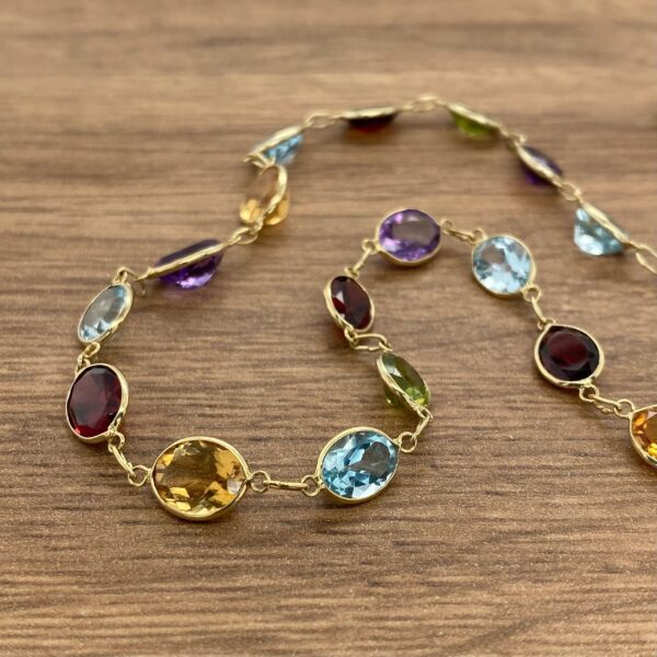 A multi colored gemstone necklace on a wooden table.