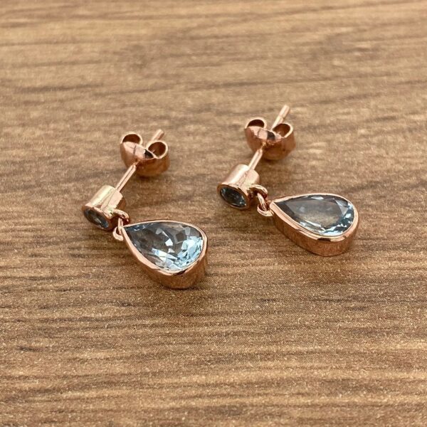 Rose gold earrings with teardrop blue stones.