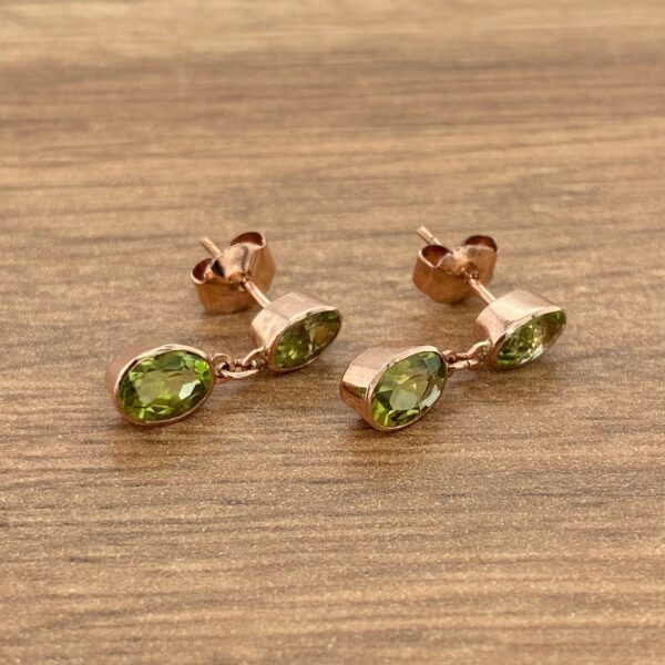 Rose gold earrings with green gemstones.