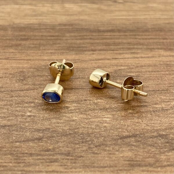 Gold earrings with blue gemstone studs.