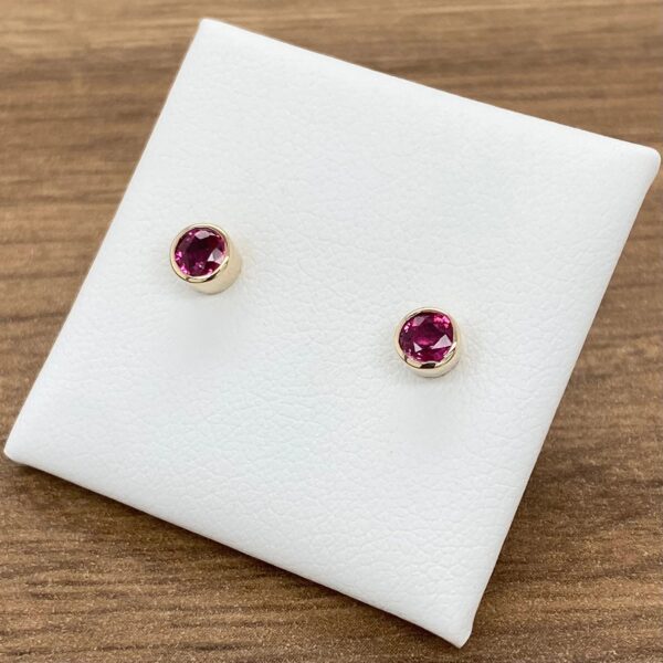 Gold stud earrings with pink gems.