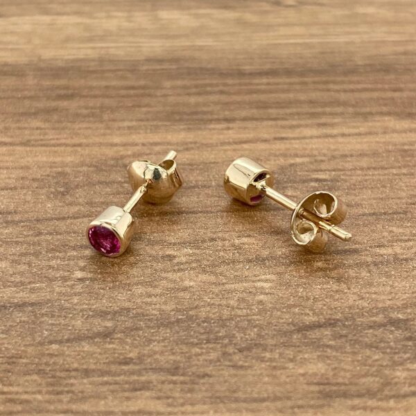 Gold stud earrings with pink gemstones.