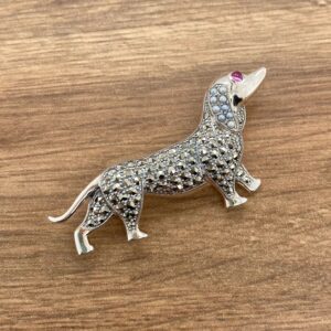 A dachshund dog brooch with pink stones.