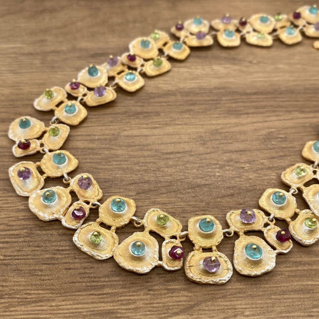 Gold necklace with colorful gemstones.