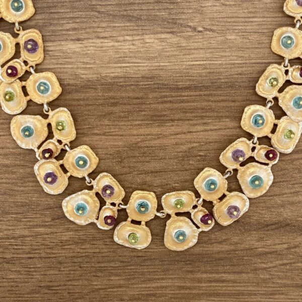 Gold necklace with colorful gemstone accents.