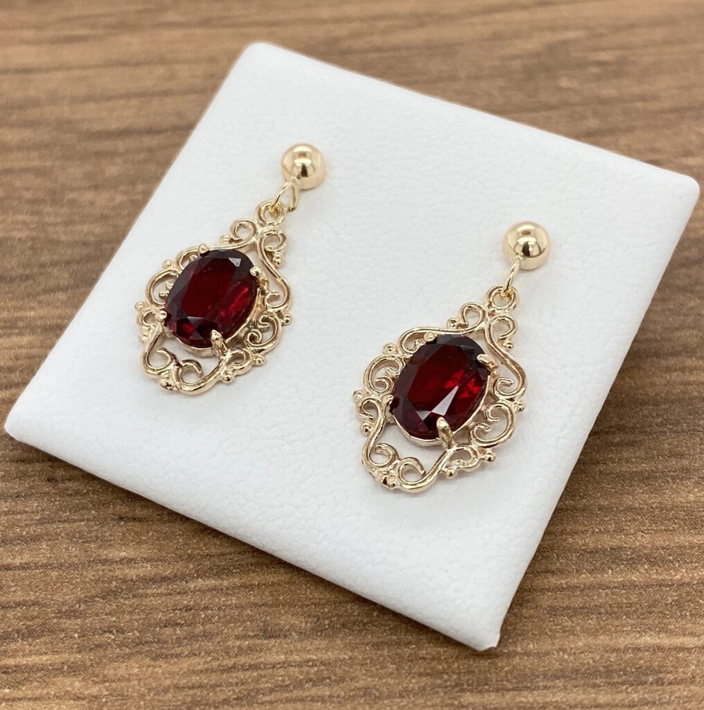 Gold earrings with red gemstone.