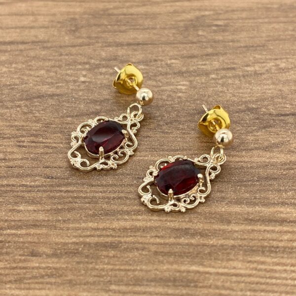 Gold earrings with red gemstone accents.