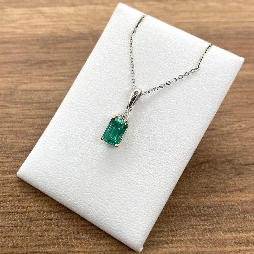 An emerald pendant on a white box.