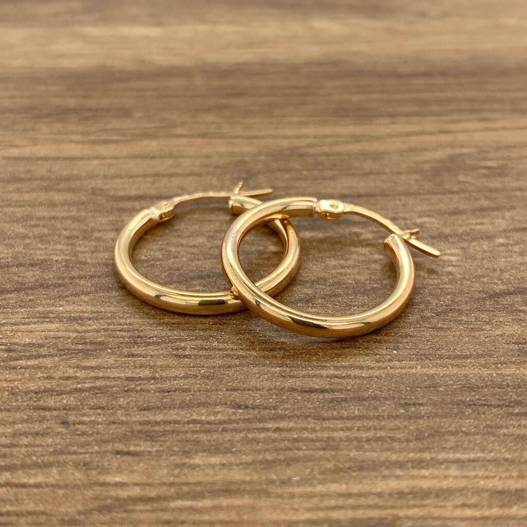 Two gold hoop earrings on a wooden table.