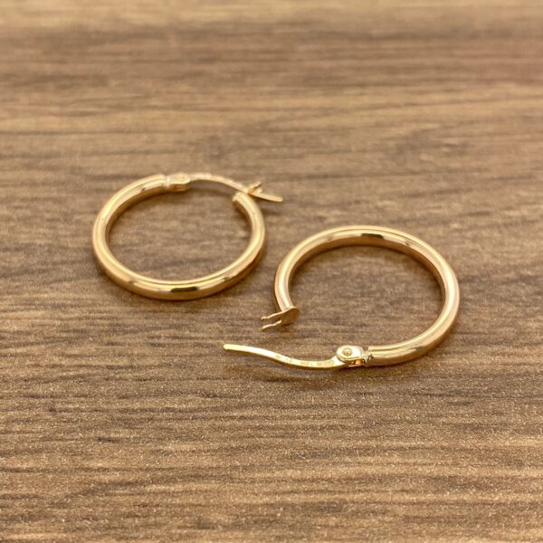 Gold hoop earrings on a wooden surface.