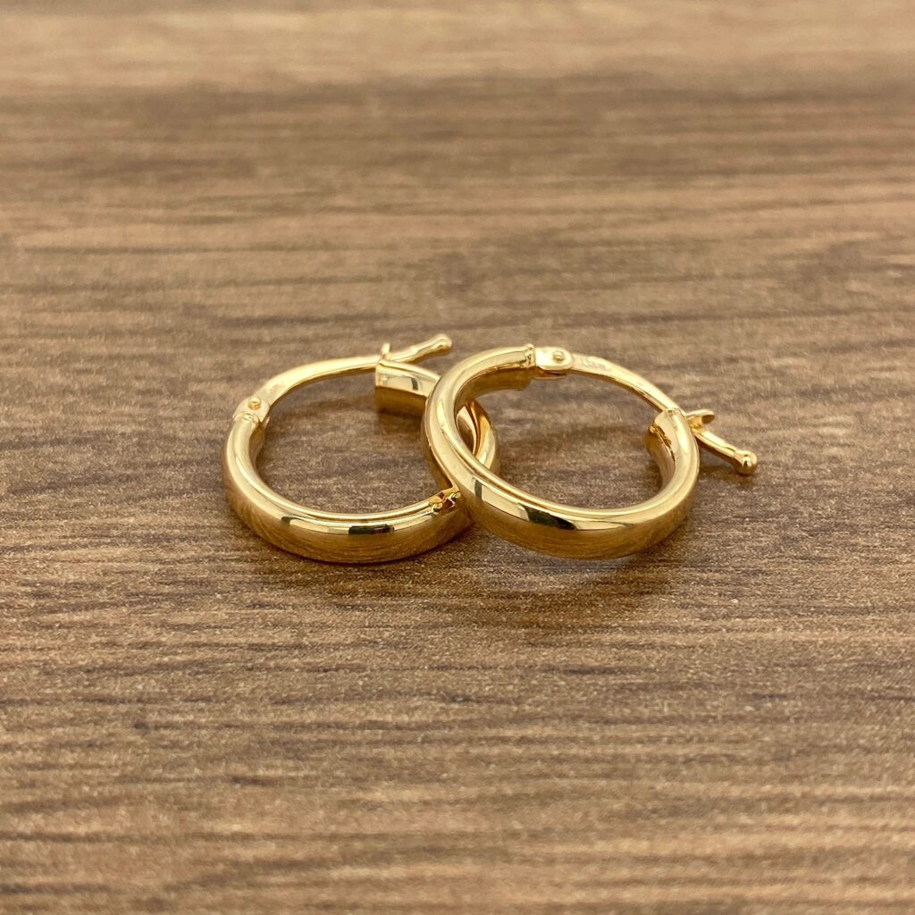 Two gold hoop earrings on a wooden table.