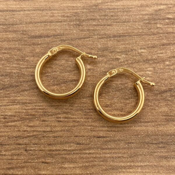 Gold hoop earrings on a wooden surface.