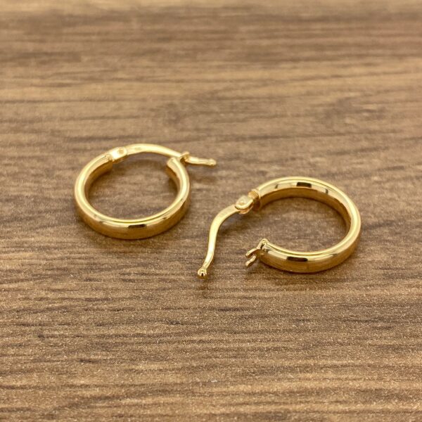 Gold hoop earrings on a wood background.