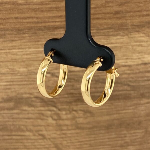 Gold hoop earrings on a display stand.