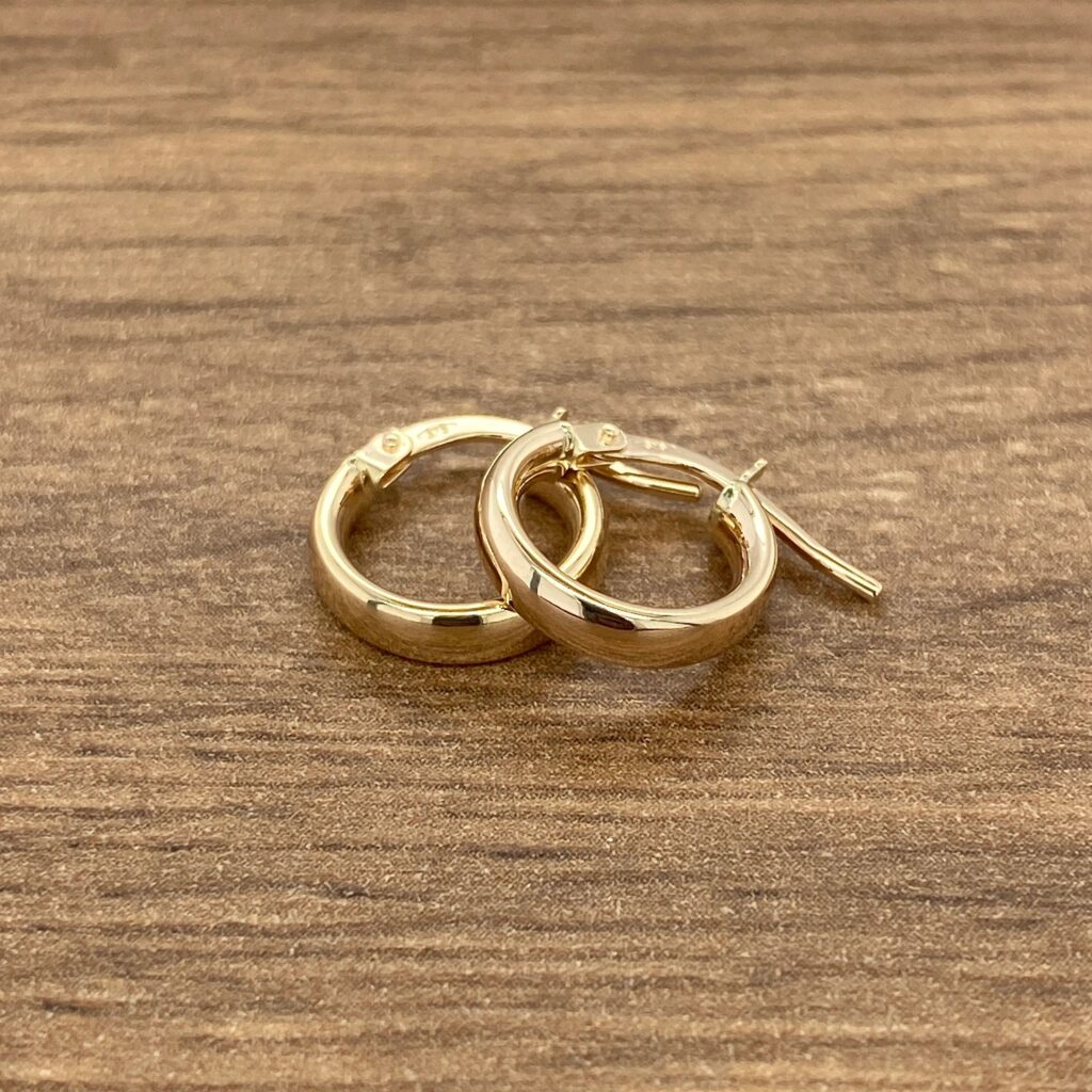 Gold hoop earrings on a wood surface.