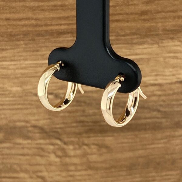 Gold hoop earrings on a black stand.