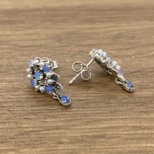 Silver earrings with opal and pearl accents.