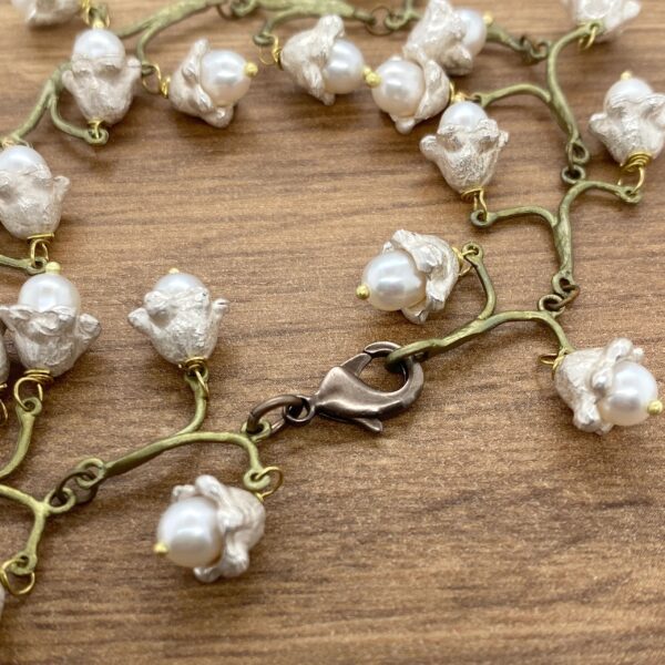 A bracelet with white pearls on a wooden table.