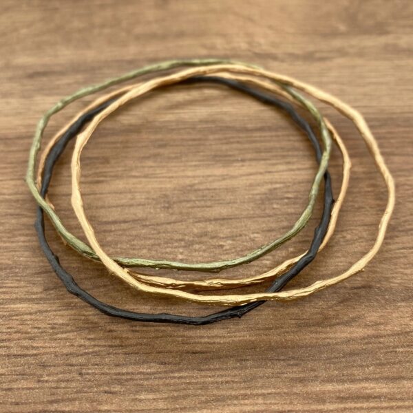 Three twig-shaped bracelets in gold, green, and black.