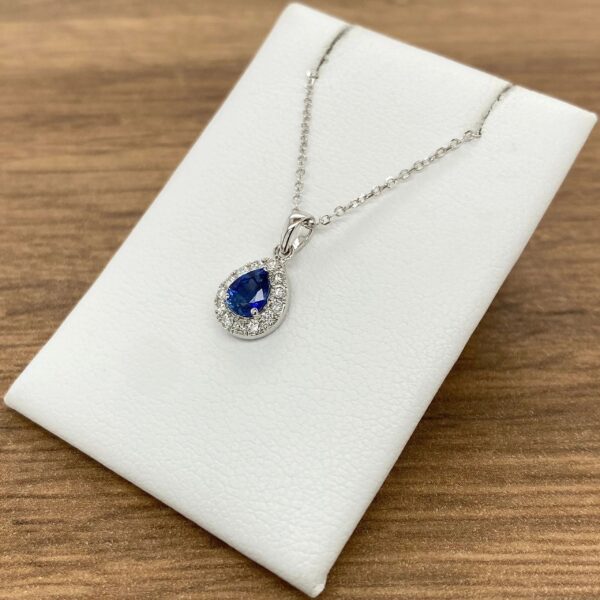 A blue sapphire and diamond necklace on a white background.