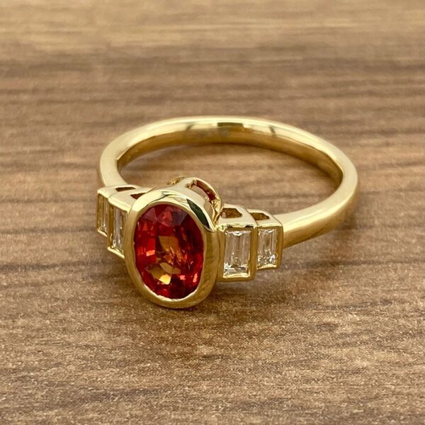 Gold ring with orange gemstone and diamonds.