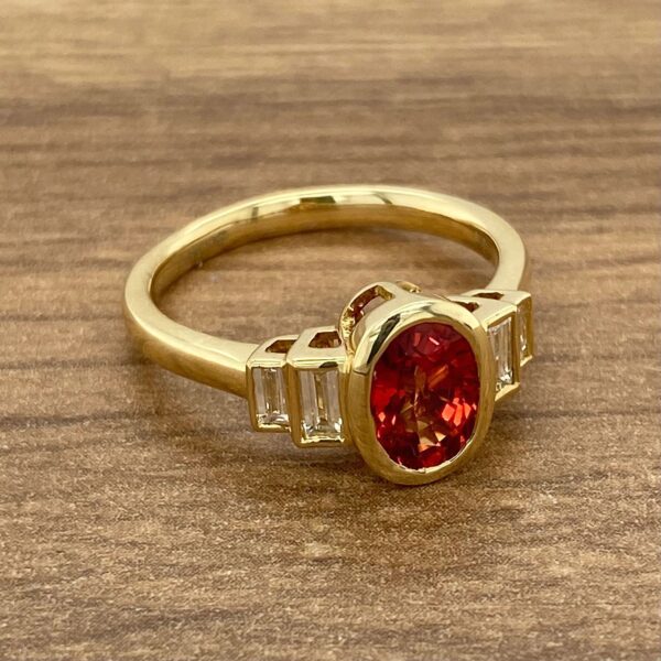 Gold ring with red gemstone and diamonds.