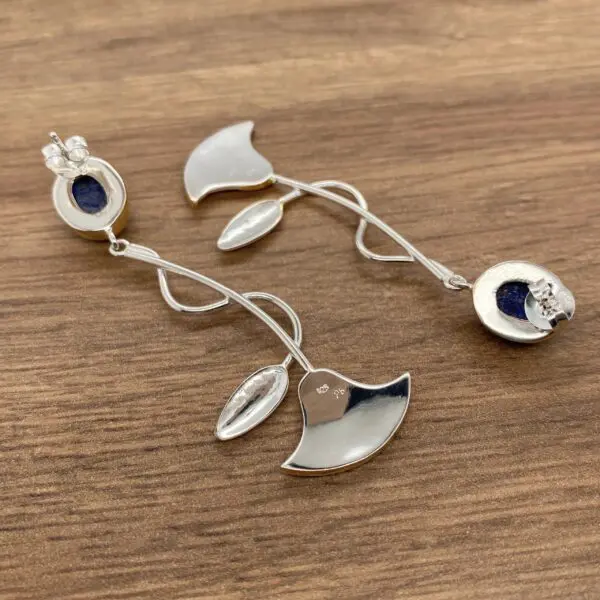 Silver earrings with blue gemstone flowers.