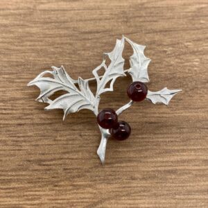 Silver holly brooch with red berries.