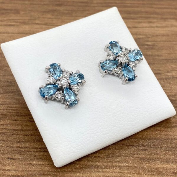 A pair of blue topaz and diamond earrings on a wooden table.