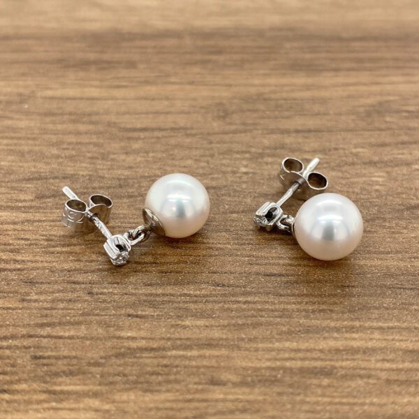 White pearl earrings with diamond accents.