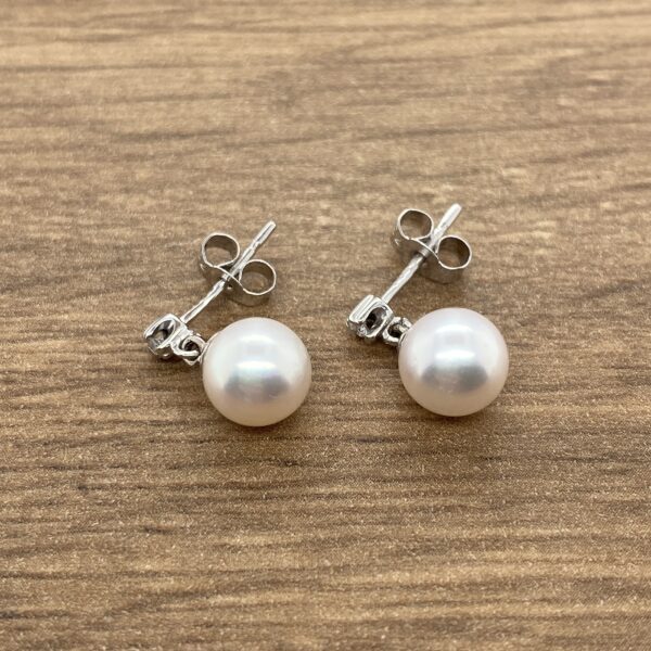 Pair of pearl drop earrings with diamond accents.