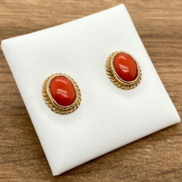 A pair of coral stud earrings on a white background.