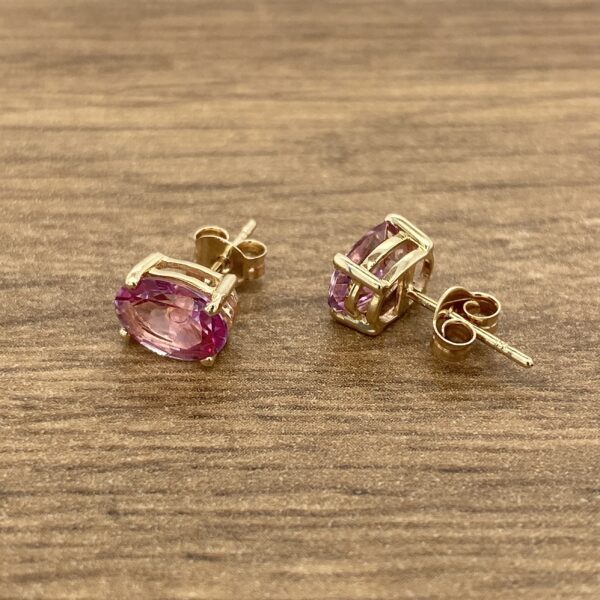 Gold earrings with pink oval gemstones.