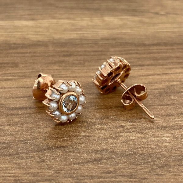 A pair of rose gold stud earrings with pearls.