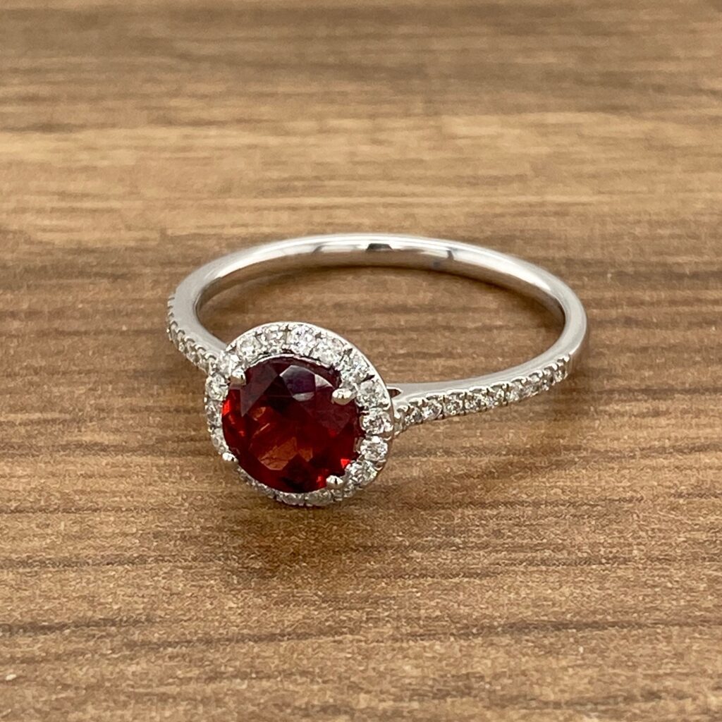 Red gemstone ring with diamond halo.