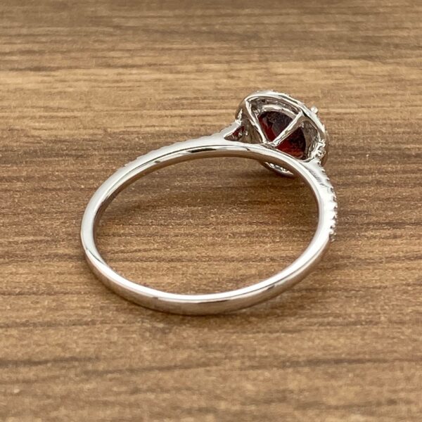 Silver ring with red gemstone and diamonds.