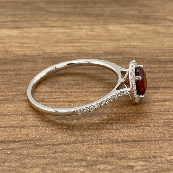 Red gemstone ring with diamond halo.