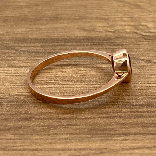Rose gold ring with red gemstone.