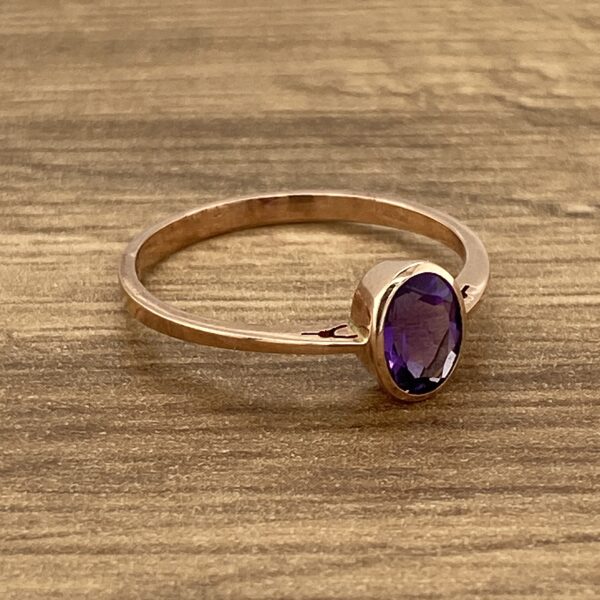 Rose gold ring with purple gemstone.