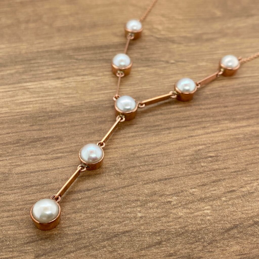 Rose gold necklace with pearl accents.