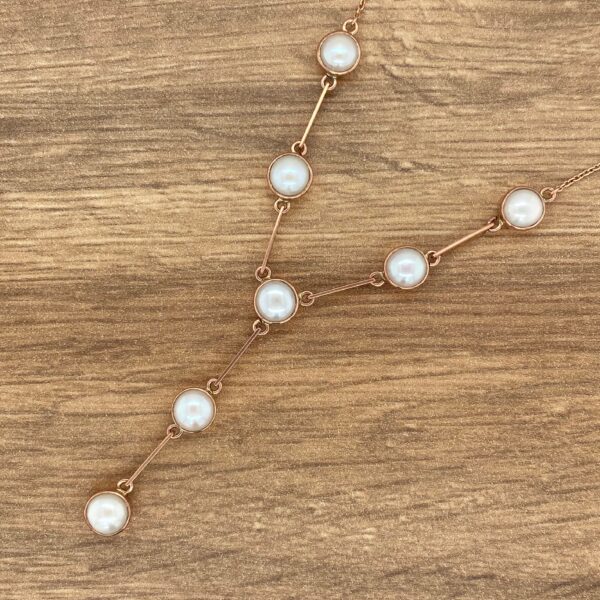 Gold necklace with white pearl accents.