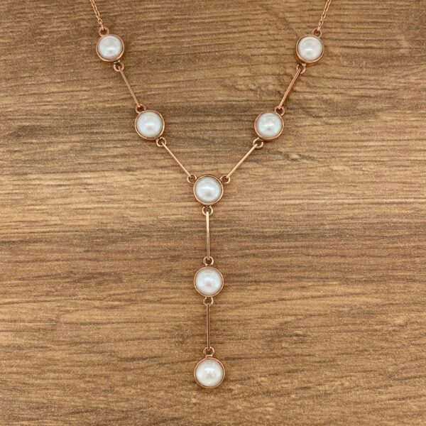 Rose gold necklace with pearl accents.