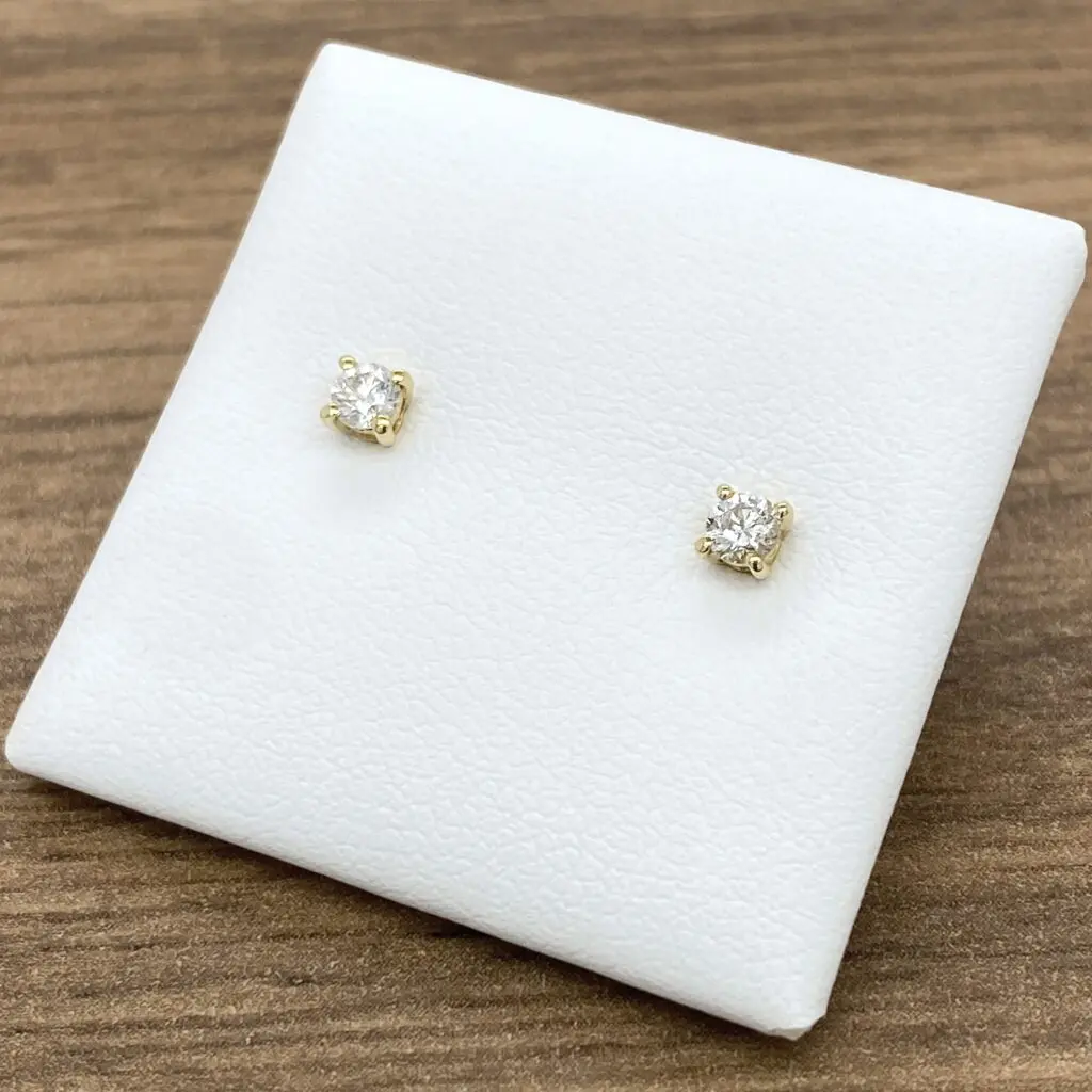 Pair of diamond stud earrings on white pad.