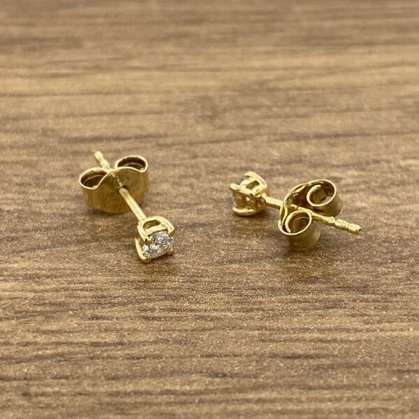 Gold stud earrings with single diamond.