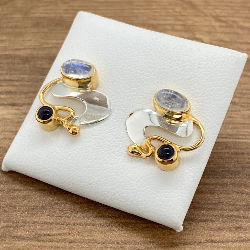 Gold and silver earrings with moonstone and black gems.