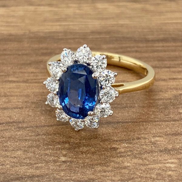 An oval sapphire and diamond ring on a wooden table.